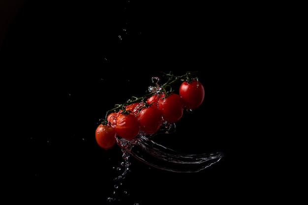 Freeze motion. Cherry tomatoes on black background with splashing water