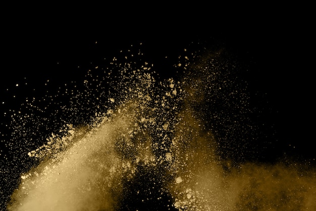 Freeze motion of golden powder exploding, isolated on black background
