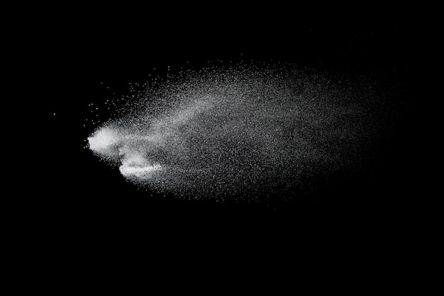 Freeze motion of white dust particles on black background. White powder explosion.