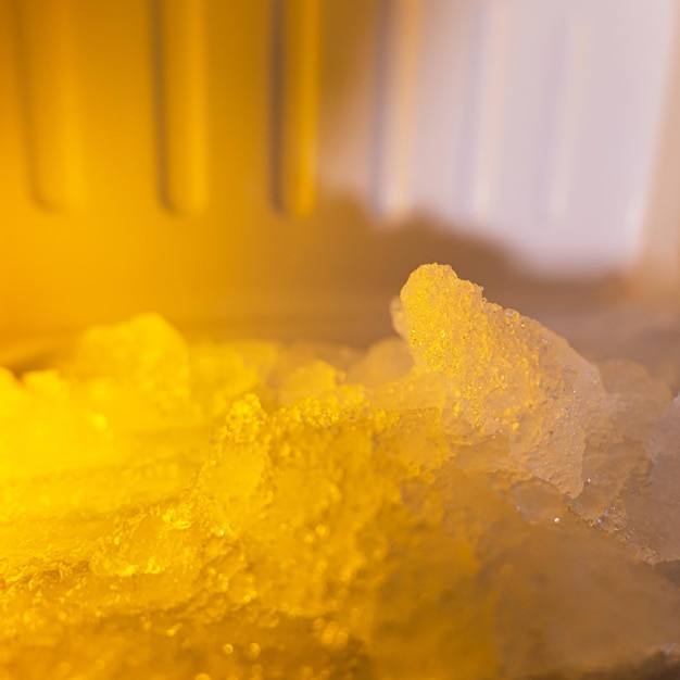 The freezer compartment of the refrigerator is heavily frozen with an orange glow