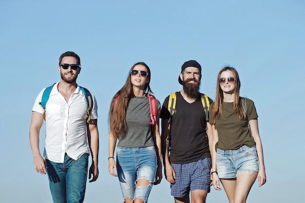 Photo freinds in jeans and shorts with backpacks walking outdoor