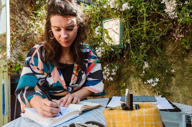 French adult woman designer drawing sketches on paper with marker working at home