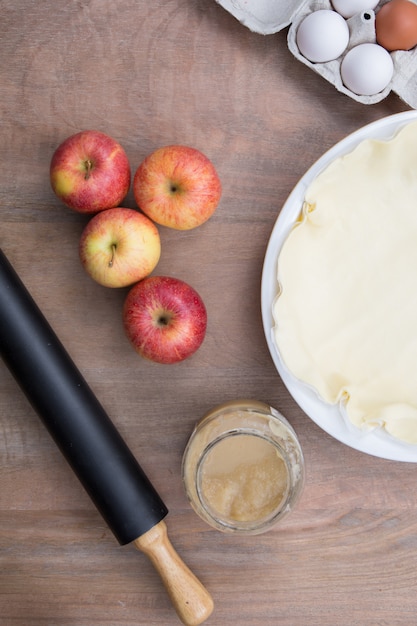 French apple pie and ingredients over rustic background