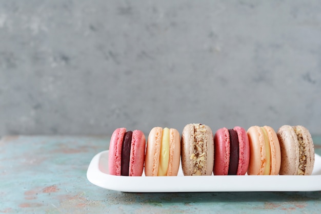 Французский ассорти macarons торты на прямоугольное блюдо. Красочные маленькие французские торты. Вид сверху.