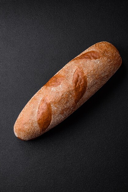 French baguette bread on a dark textured concrete background making delicious bruschetta at home