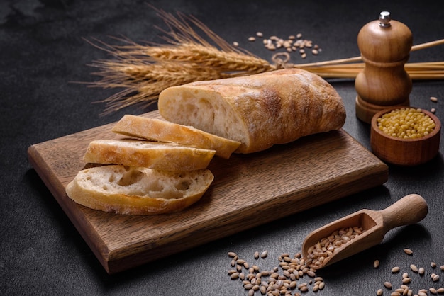 French baguette bread sliced on a wooden cutting board against a dark concrete background