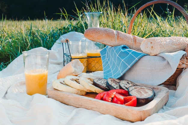 French baguette, orange juice and stewed vegetables on a picnic