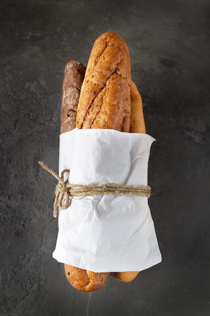 French baguettes wrapped in white paper on a dark background