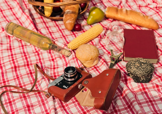 사진 과일, 바게트, 책, 체크 무늬 빨간색 식탁보 야외에 레트로 카메라와 함께 프랑스 바구니
