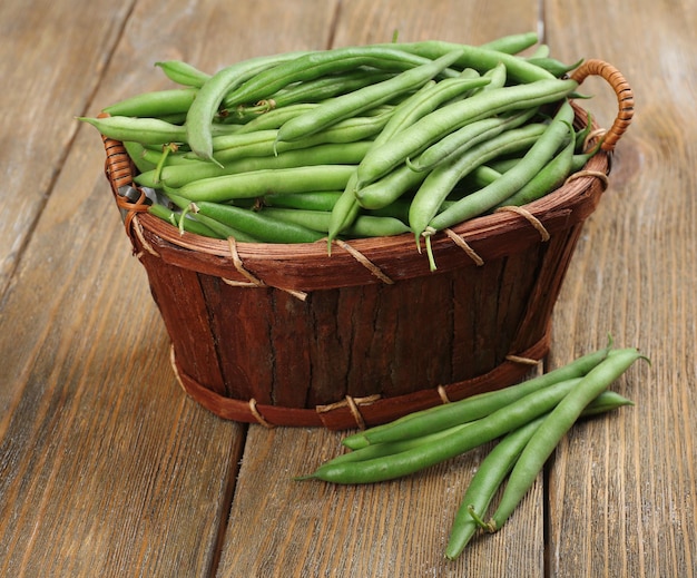 French beans in wooden basket on table closeup