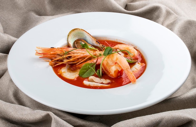 French bouillabaisse fish soup with shrimp mussels and scallop In a white plate on a textile background