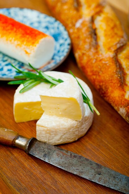 Photo french cheese and fresh baguette on a wood cutter