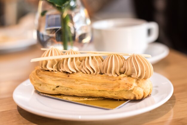 french coffee eclair on plate with cup of tea