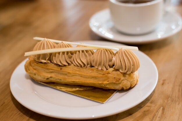 french coffee eclair on plate with cup of tea