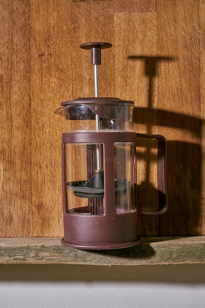 French coffee press on a wooden kitchen shelf.