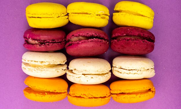 Фото Французские красочные макаронные печенья, выделенные на фиолетовом фоне