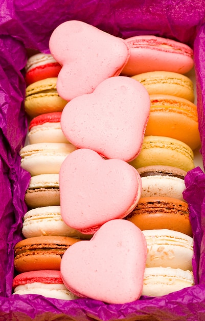 French colorful macarons with hearts on violet background