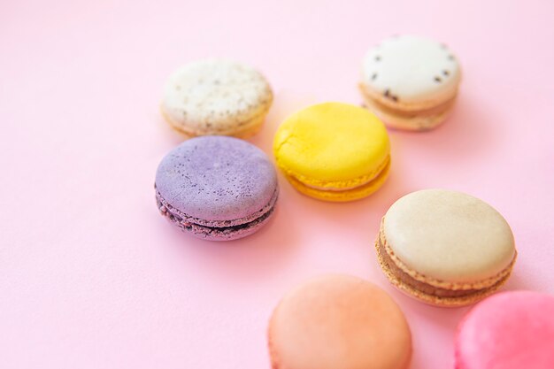 French colorful macaroons cakes flat lay isolated on pink background
