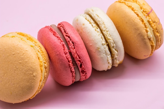 ピンクの背景に設定されたフランスのクッキーマカロンおいしいフルーツアーモンド甘いクッキーケーキマカロン