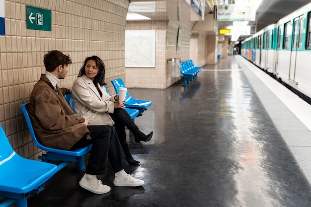 Photo french couple waiting for the subway train and drinking coffee