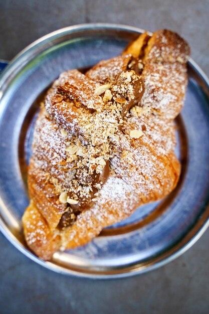 Foto croissant francese per la colazione in un caffè fresco delizioso croissant dolce al forno con cioccolato e caramello su un tavolo di caffè al mattino focus selezionato