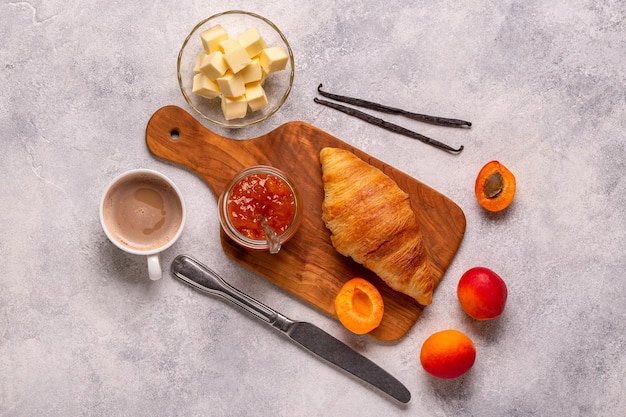 French croissant Freshly baked croissants with jam butter coffee on a dark stone background