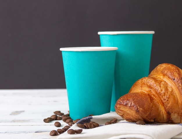 French croissant with take-away coffee in paper cup. Free copy space.