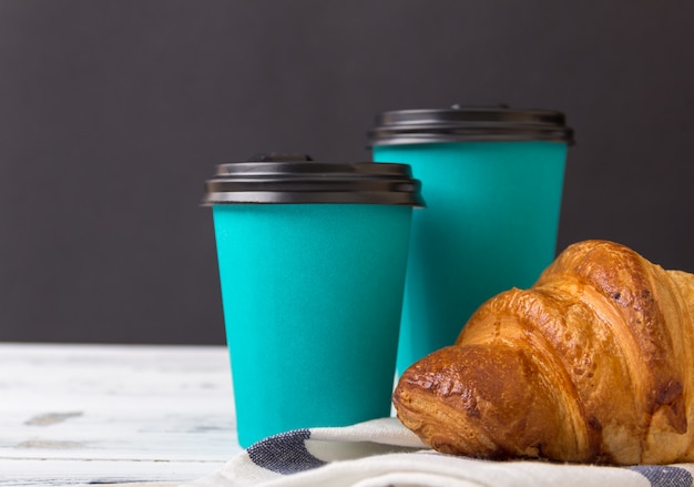French croissant with take-away coffee in paper cup. Free copy space.