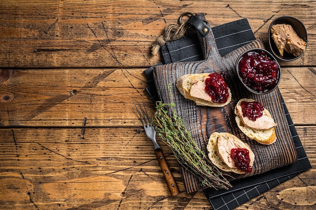 French cuisine Foie gras toasts goose liver pate and lingonberry marmalade wooden background Top view Copy space