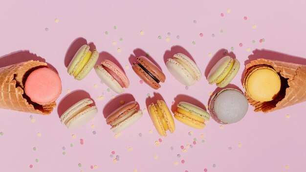 French dessert concept colorful macarons are served in waffle cone and falling on pink background