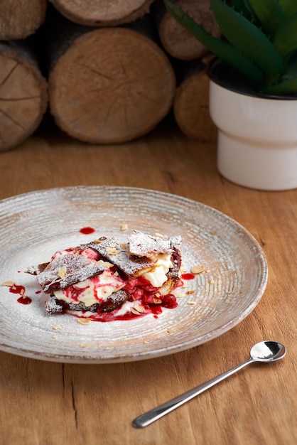 French dessert millefeuille of puff pastry and custard and ice cream on a plate and on a wooden table closeup