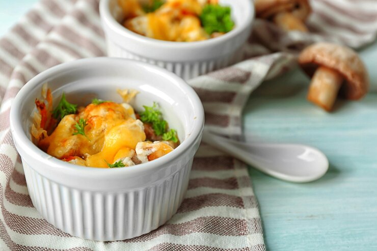 Photo french dish julienne mushroom chicken and cheese gratin in ceramic bowls on wooden background