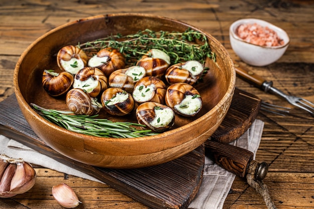 French Escargot Snails with garlic butter in a wooden plate. Wooden background. Top view.