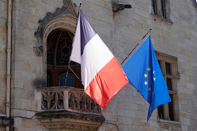 Bandiera francese ed europea dell'ue che sventola davanti al tappeto davanti al municipio nella città della francia