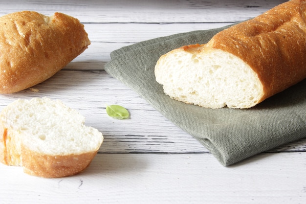 French fresh soft bread baguette on napkin and wooden background