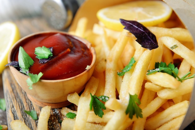 French fried potatoes in craft paper on cutting board