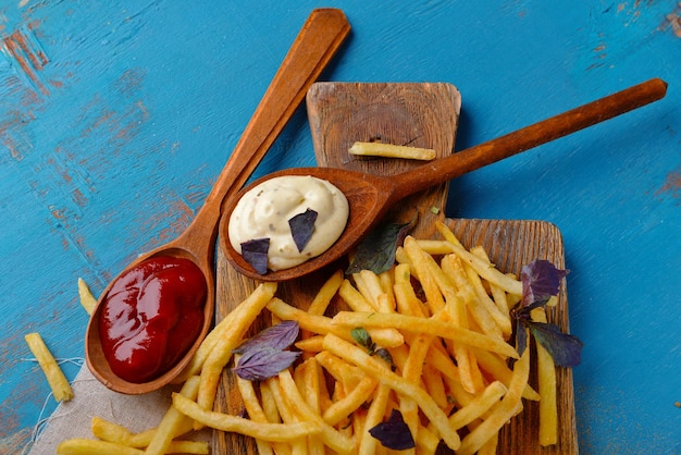 French fried potatoes with sauce on cutting board