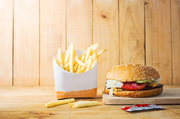 Foto patatine fritte, hamburger, fast food su un tagliere di legno