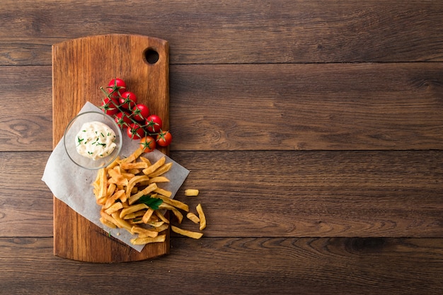 French fries, cherry tomatoes, garlic sauce on wood