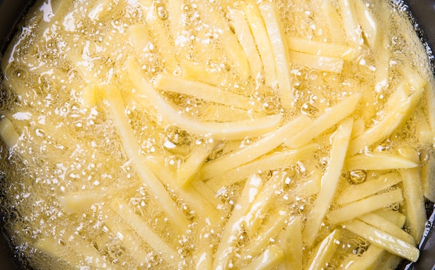 Photo french fries cooking in oil in a deep fryer.