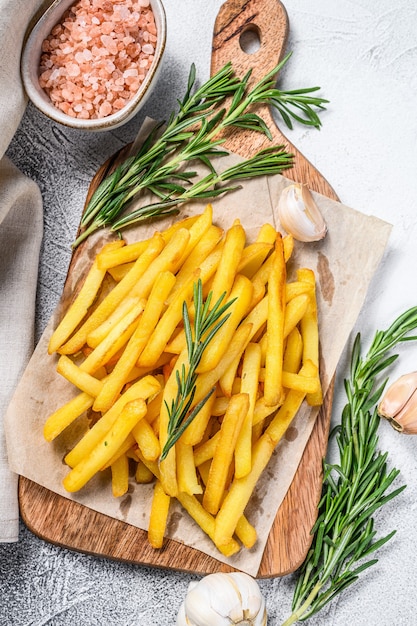 French fries on a cutting board, fried potatoes. White background. Top view.