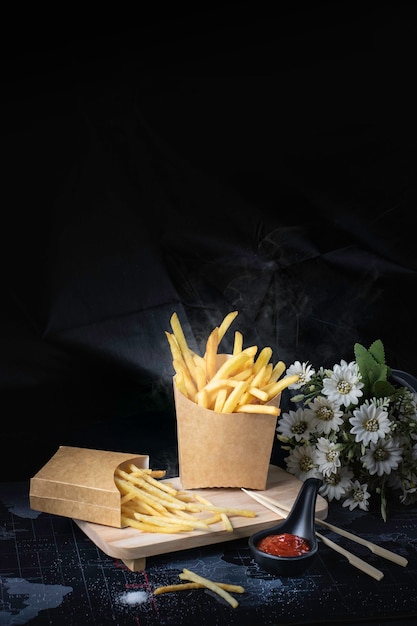 French fries fried yellow on a black background with smoke