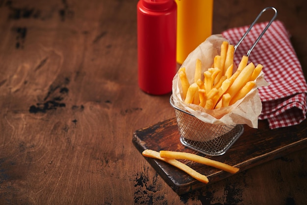 French fries in a metal mesh basket on a wooden board fast food concept american food