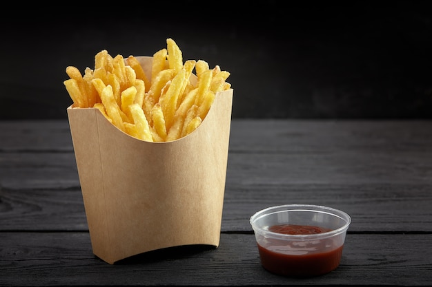 French fries in a paper basket. Fast food.French fries in a paper box on black background