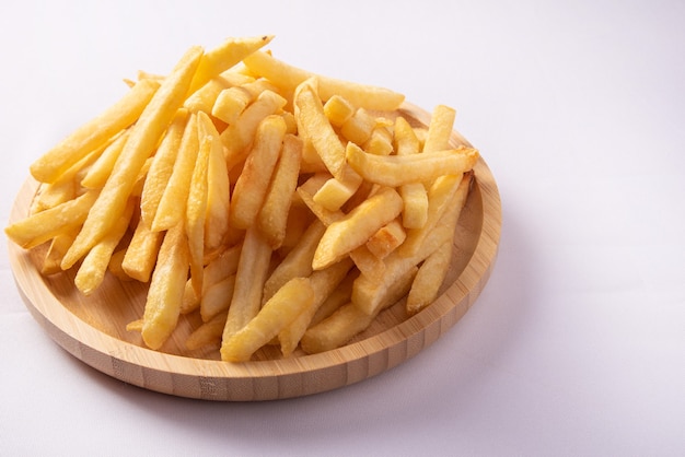 French fries placed on a round wooden plate.