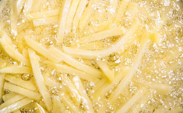 Photo french fries potatoes frying in boiling oil.