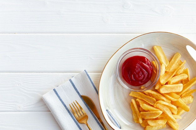 French fries potatoes in plate with sauce on wooden table close up