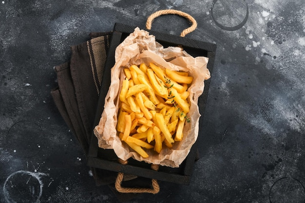 Patatine fritte gustose patatine fritte server su carta pergamena su tagliere di legno con salsa di pomodoro e formaggio su vecchio sfondo nero diversi piatti keto fast food e concetto di cibo malsano