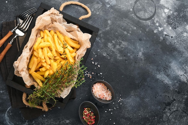 French fries Tasty French fries server on parchment paper on wooden cutting board with tomato and cheese sauce on old black background Diverse Keto Dishes Fast food and unhealthy food concept