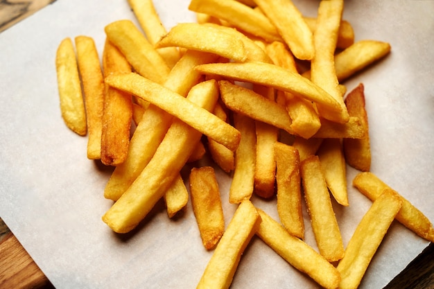 French fries on white paper background, close-up. Fresh and crispy french fries